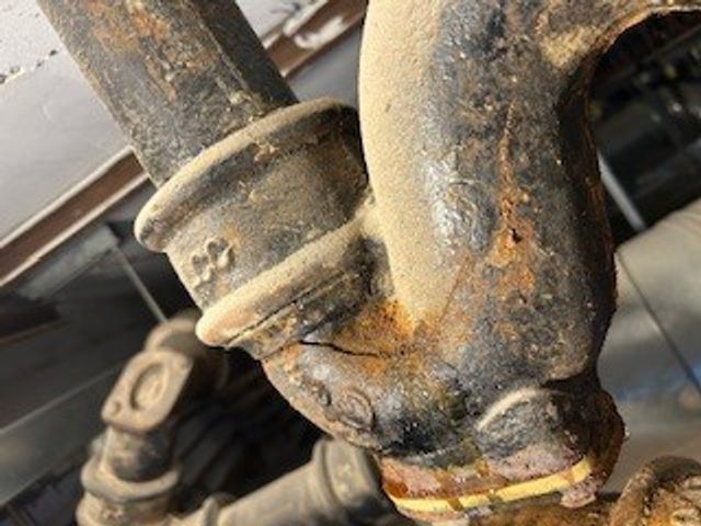 A hairline crack in a cast iron waste pipe U-bend before undergoing repair with a SylWrap Drain & Waste Pipe Repair Kit