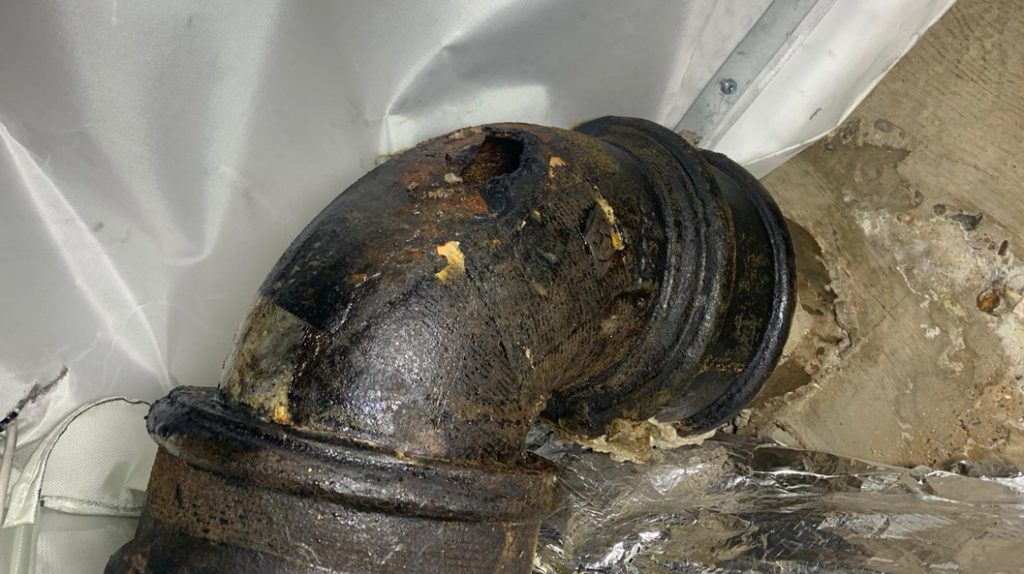 A large crack in a cast iron wastewater pipe required repair in a London Hotel