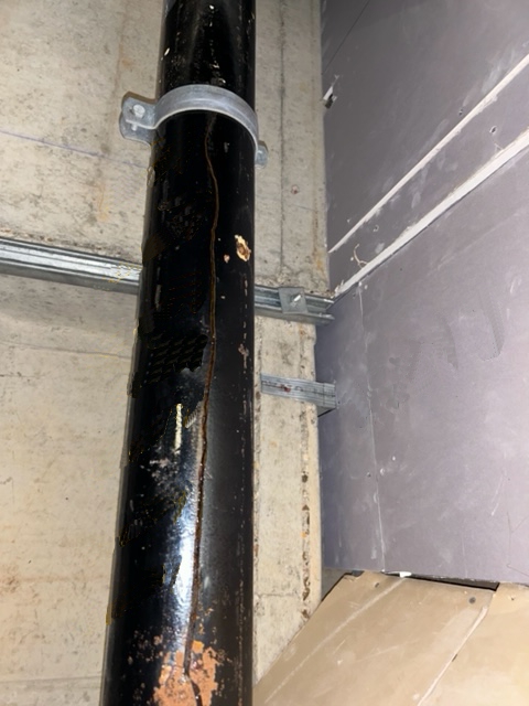 A split in a cast iron downpipe before undergoing repair with a SylWrap Drain & Waste Pipe Repair Kit