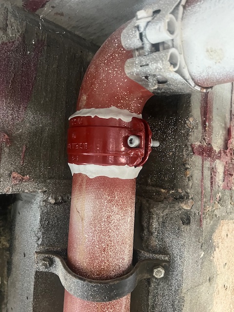 Leaking pipe repair clamp sealed using epoxy putty in the refurbishment of a 250-metre long cast iron rainwater stack