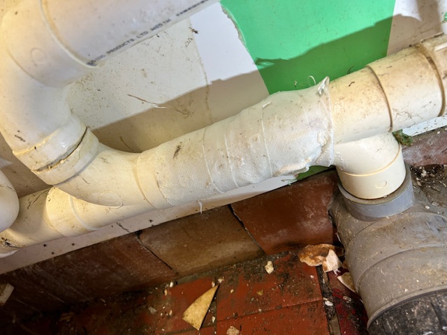 Leaking dishwasher pipe at a UK golf club after undergoing repair using SylWrap Universal Pipe Repair Kit 