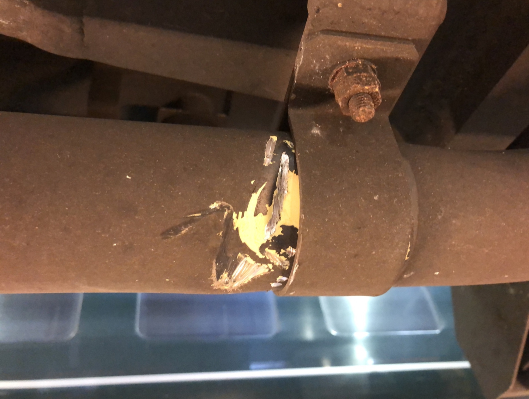 Aluminium conduit pipe underneath a train damaged by loose track ballast before undergoing repair with SylWrap HD