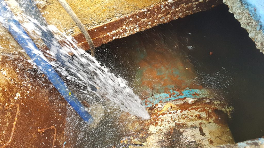 Pressurised water escaping from a water main leaking from a flange in Malaysia prior to repair