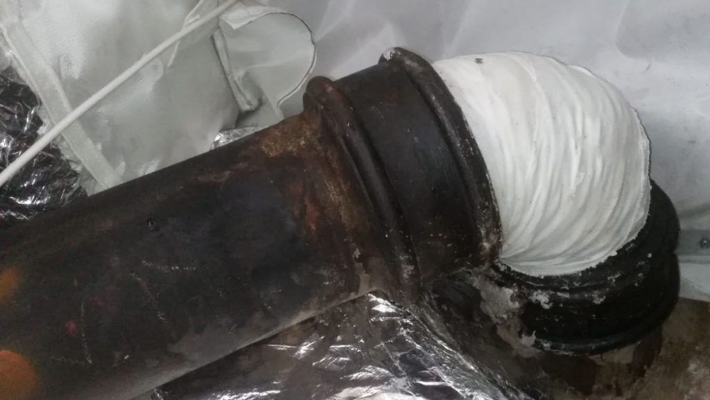 SylWrap HD Bandage wrapped around a cracked cast iron wastewater pipe during a repair in a London hotel