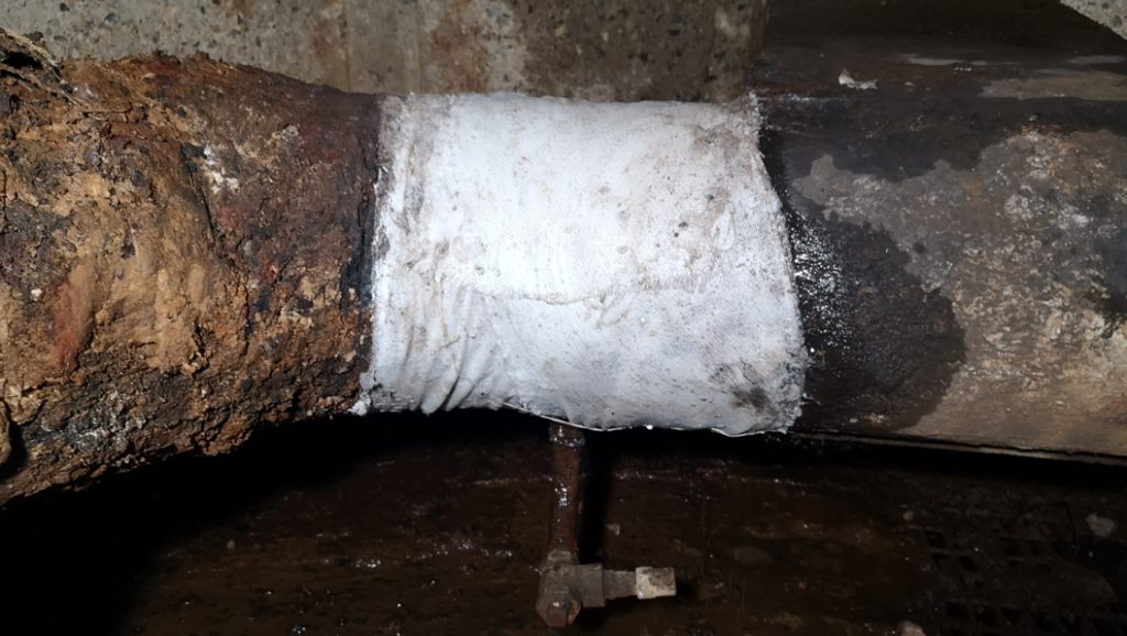 Badly corroded pipe in a district heating system undergoes repair with a SylWrap HD Pipe Repair Bandage