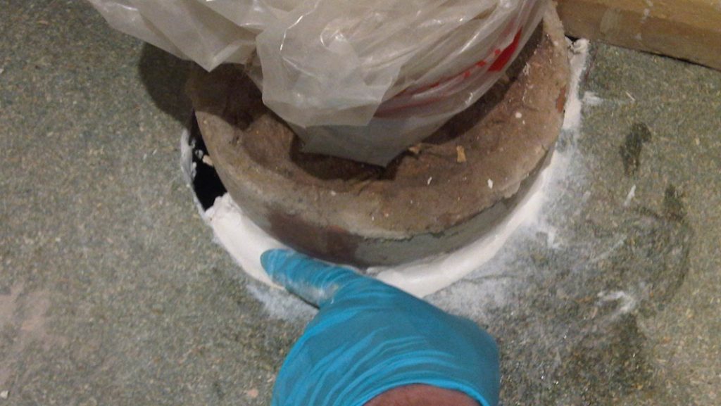 Epoxy putty applied to a cracked area between a toilet waste pipe and a bathroom floor accidentally left during renovation work