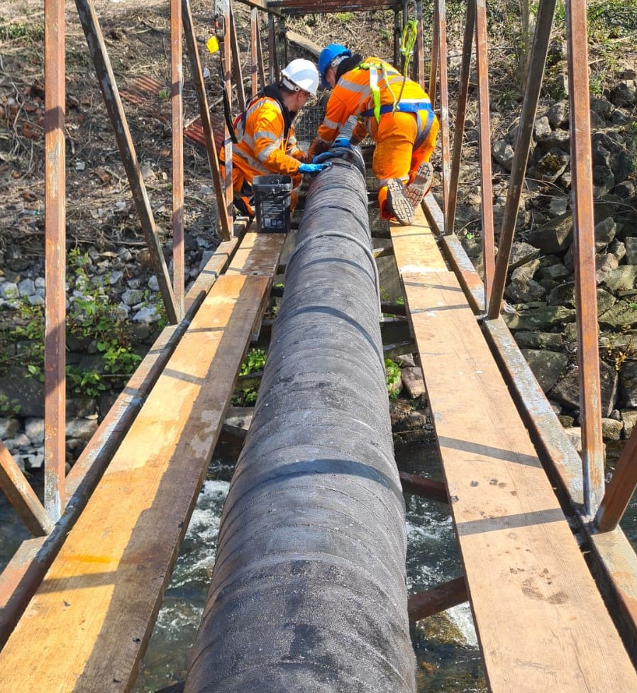 Arch Services of Porth carrying out the refurbishment of a heavily corroded steel pipe crossing the Rhonda River