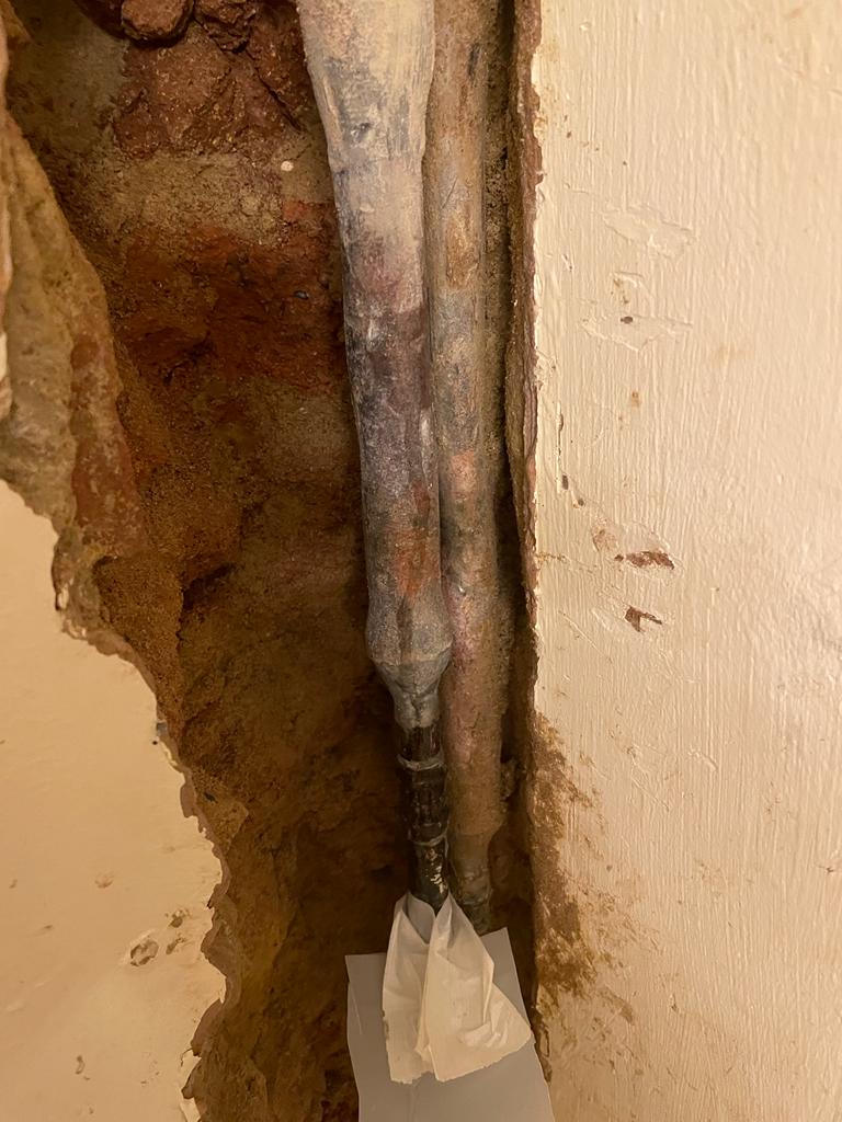 Leaking lead pipe contained within the wall of a home in the United Kingdom before undergoing repair