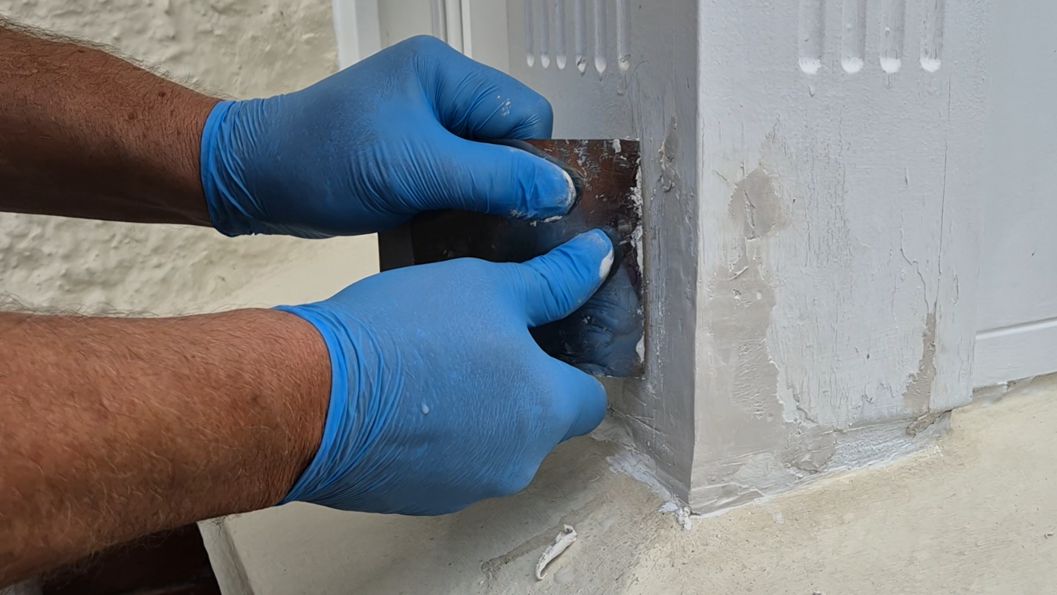 Metal spreader being used to smooth off AB Original Epoxy Putty during the repair and rebuild of a rotted bay sash window frame